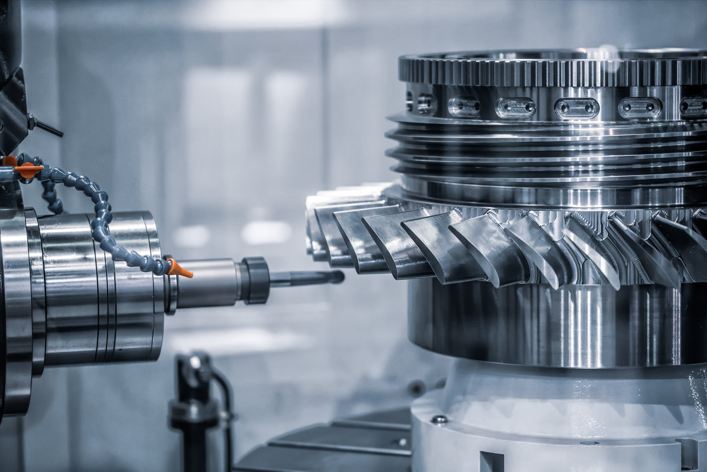 A close-up industrial scene showing a large machined turbine component with a milling tool approaching it in a clean factory setting.