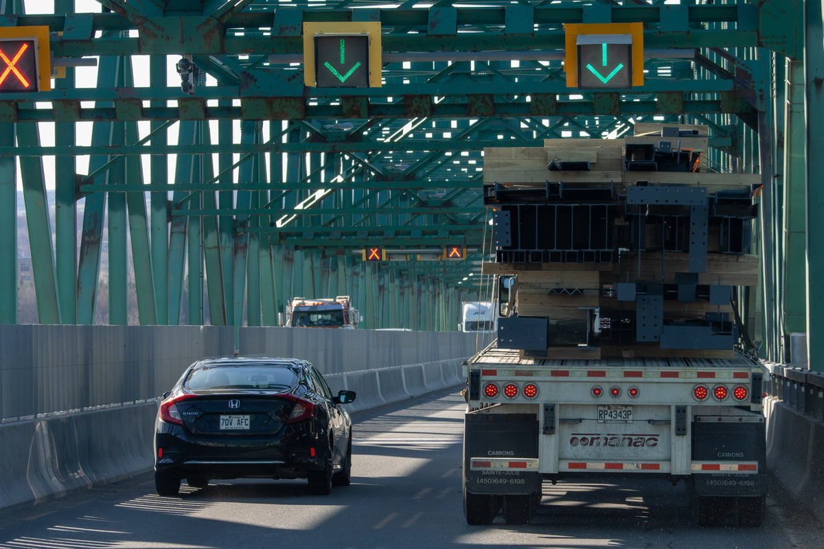 car and truck driving on bridge at traffic light