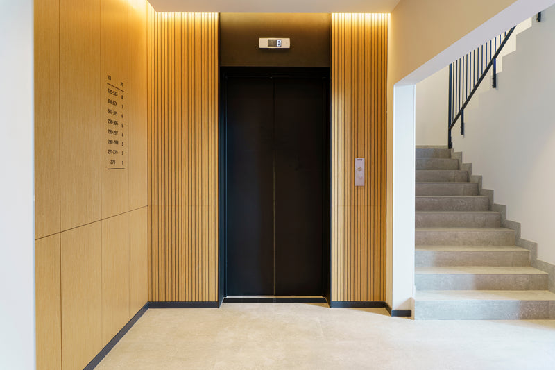 Elevator with wooden paneling on the sides and a staircase leading upwards.