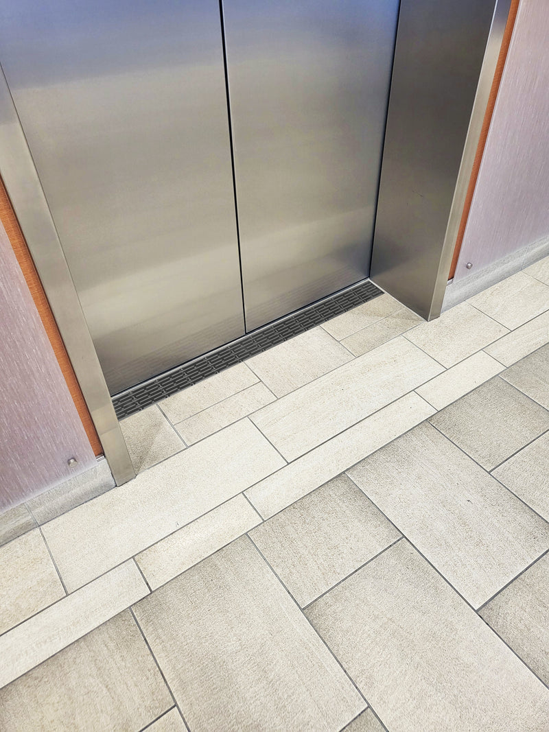 Elevator threshold drain closeup with tile floors