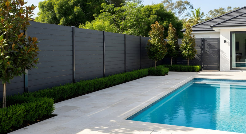 Pool area with fence and trees with a building in the background