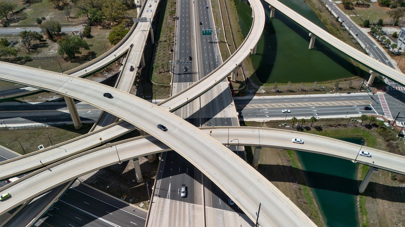 Aerial view of a complex road interchange with multiple levels and ramps with vehicles on the roads.