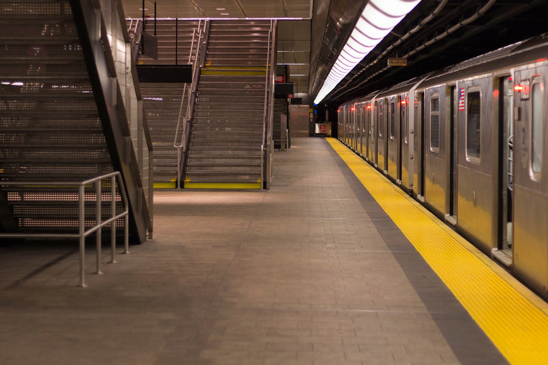empty subway station, with train at platform and stairs to next level