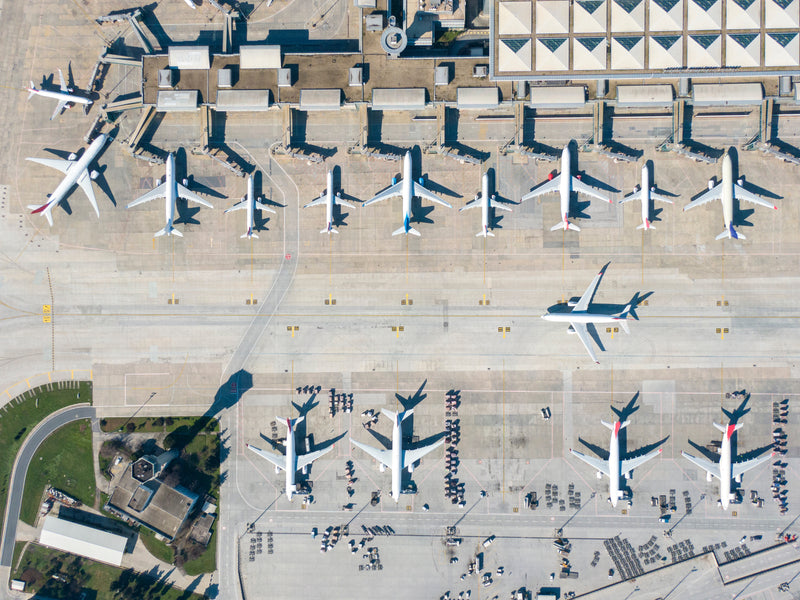 Aerial view of a busy airport with multiple airplanes of multiple sizes parked at the terminal.