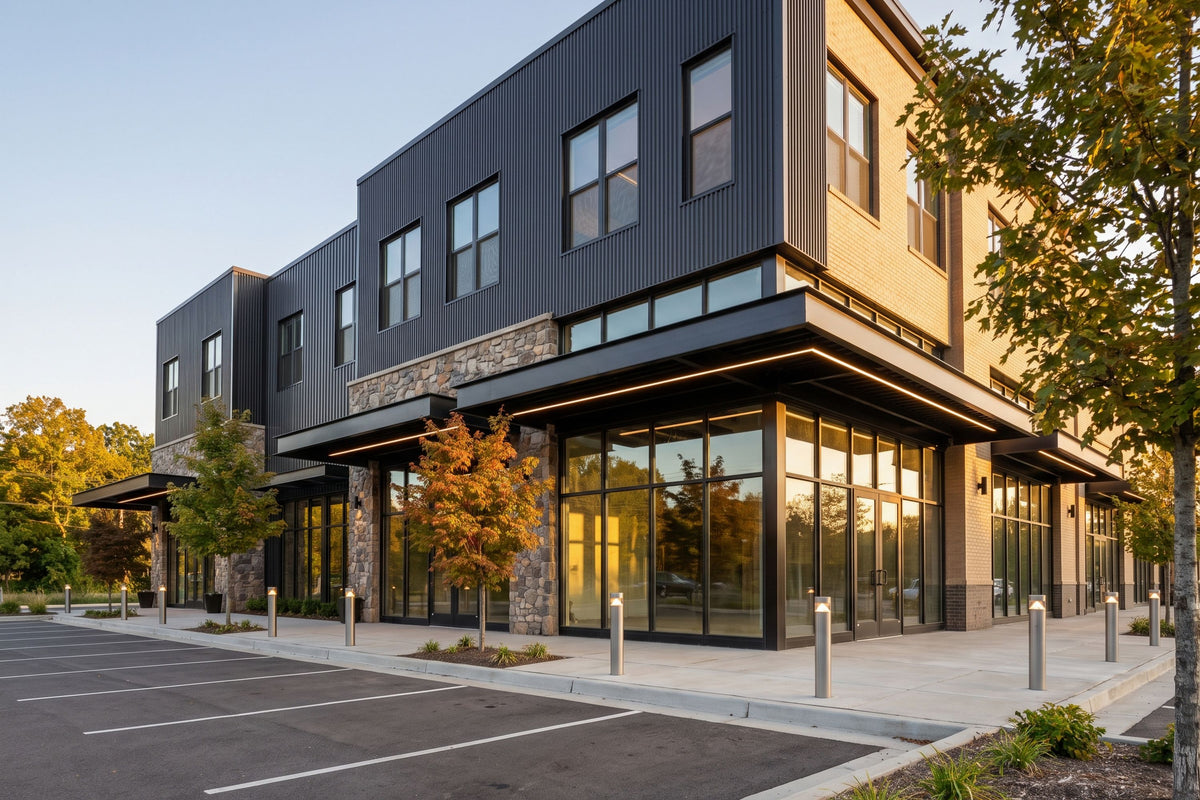 Exterior view of a modern two-story mixed-use building featuring dark metal siding, stone accents, glass storefronts, and a paved parking lot.